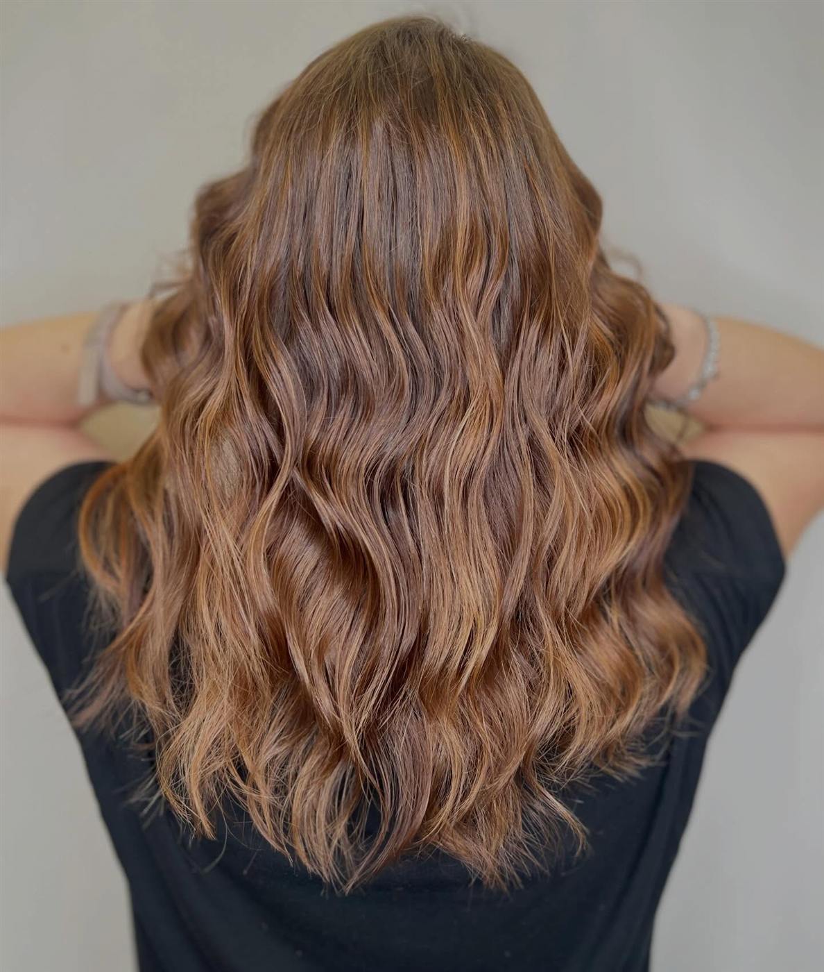 Castano con balayage caramello su lunghezze mosse, vista da dietro